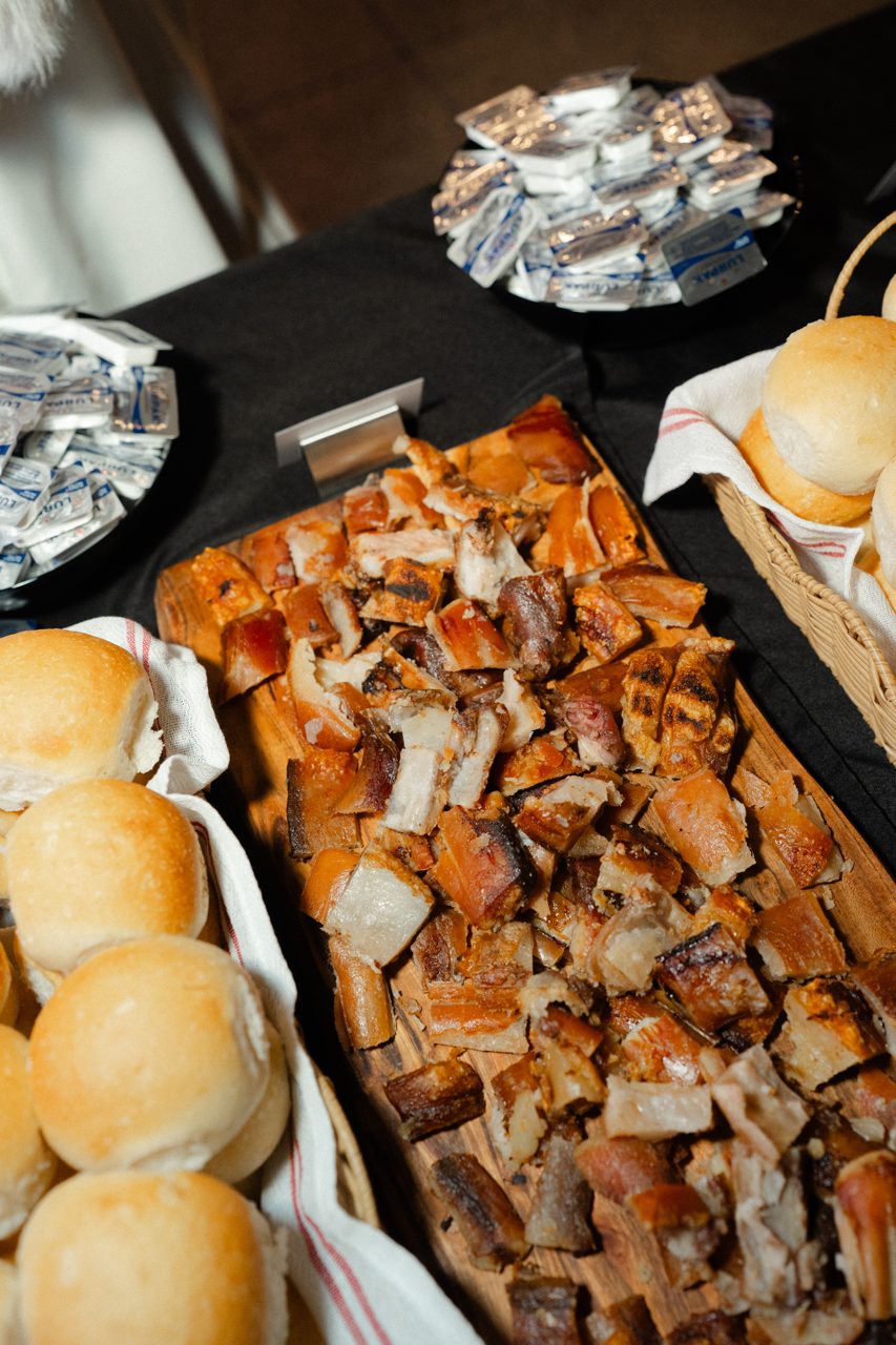 Roast pork belly carved on a board with fresh rolls